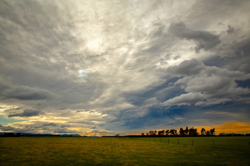 Naklejka premium Storm clouds gather overhead and bright light filters through the gaps to the fields below