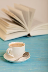 Book and cup of coffee on a wooden blue background.