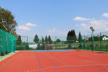 Naklejka premium Lubno, Poland - july 9 2018:An open stadium in the courtyard of a village school. Eduction of the younger generation. Sports ground for football, volleyball and basketball. Lighting on natural sources