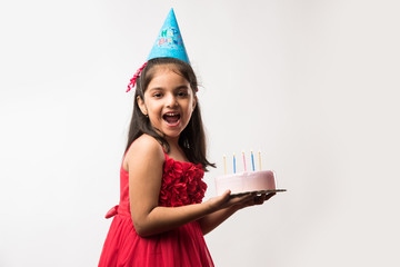Cute adorable little Indian/asian small girl celebrating birthday while holding strawberry cake and...