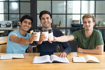 Group of multiethnic interns celebrating passing test and enjoying coffee. Young Indian and...