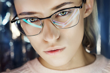 Portrait of a woman in neon colored reflection glasses in the background. Good vision, perfect makeup on girl face. Art portrait of a flare and bokeh on the glasses. Vision restoration, eye surgery