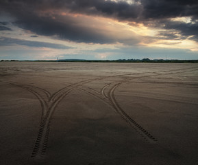 tire tracks on the sand at sunset