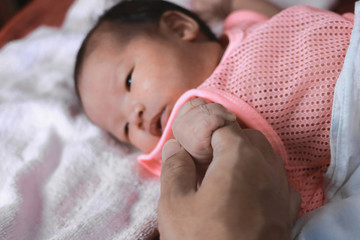 Soft focus of newborn tiny baby hand on parent.