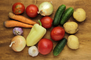 raw vegetables tomatoes cucumers potatoes onions carrots garlic on wooden surface