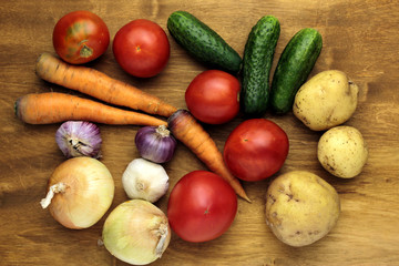 raw vegetables tomatoes cucumers potatoes onions carrots garlic on wooden surface