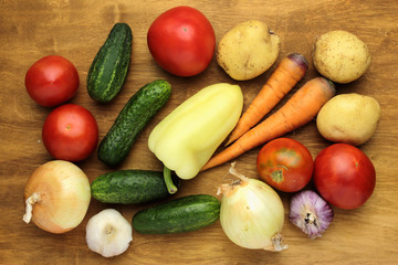raw vegetables tomatoes cucumers potatoes onions carrots garlic on wooden surface
