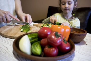 mom and daughter cut salad in the kitchen