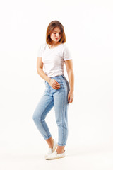 Obraz premium Girl teenager in white t-shirt and jeans poses in white studio, full body