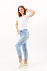 Obraz premium Beautiful girl teenager in white t-shirt and jeans poses in white studio, full body