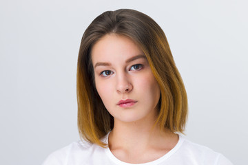 Pretty serious girl teenager in t-shirt poses in white studio