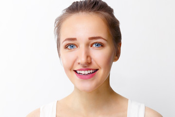 Pretty young girl with make-up smiles in studio, close up portrait