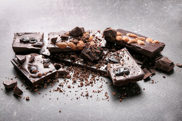 Pieces of chocolate with almonds and dried fruits on table