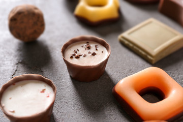 Delicious candies with chocolate on grey background