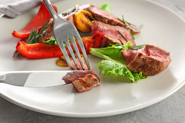 Cutting tasty meat on plate, closeup