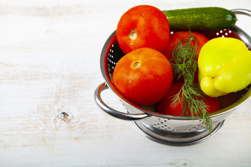 Tomatoes, peppers and cucumbers in a colander
