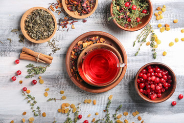 Composition with glass cup of hot aromatic tea on wooden table