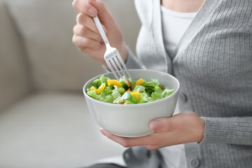 Fototapeta na wymiar Young woman eating fresh salad at home. Healthy food concept