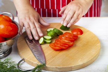 Woman is cutting vegetables for a salad