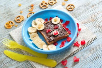 Plate with creative sweet toast for child on wooden table