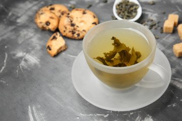 Cup of hot aromatic green tea on table
