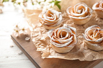 Tasty apple roses from puff pastry on wooden board