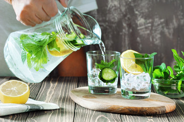 Detox water with lemon, cucumber and mint on rustic wooden background.Man preparation detox.