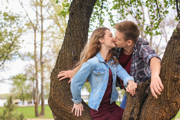 Happy young couple near tree in park on spring day