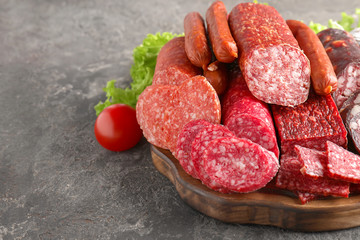 Wooden board with variety of delicious sausages on table