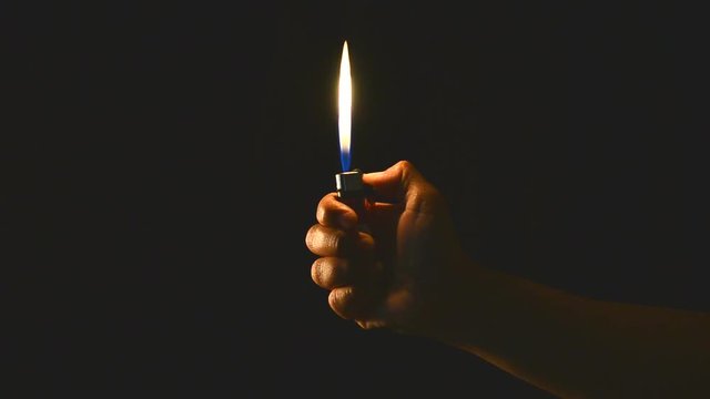 hand hold a lighter in the dark