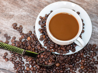Hot coffee in white cup with coffee beans on wooden table with copy space.