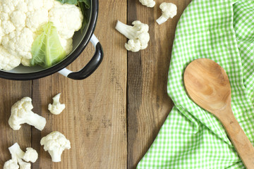 Fresh cauliflower in a colander and wooden spoon  on an old  table 
