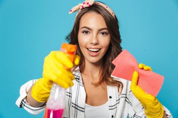 Portrait closeup of smiling woman 20s cleaning with sponge and detergent sprayer wearing yellow...