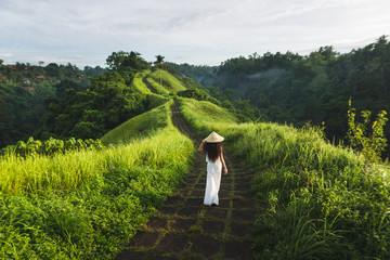 Young beautiful woman walking on Campuhan Ridge way of artists, in Bali, Ubud. Beautiful calm sunny...