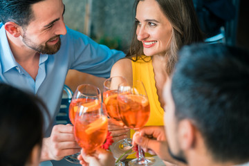 Four friends holding stemmed wine glasses while toasting together with a cold refreshing alcoholic drink during a delicious lunch at the restaurant