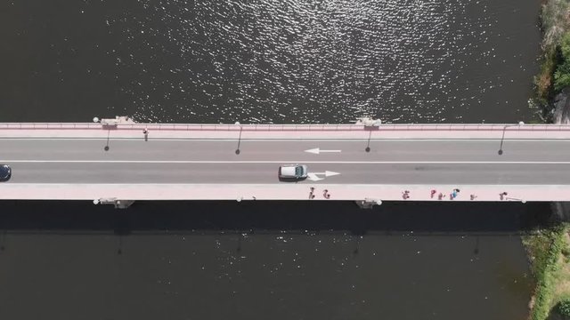 Aerial view of a bridge over a river with traffic and canoes sailing under it
