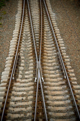 Fototapeta na wymiar Railway branching. Railroad tracks. Rails. Crossing the rail. Weaving the rail in front of the train station. Selecting the path. Option of choice. Railway junction. Portrait orientation photo.