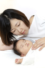 Obraz na płótnie Canvas 新生児と添い寝しながら赤ちゃんを見つめる母