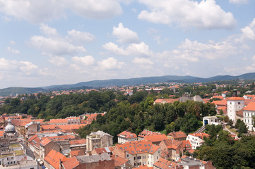 Fototapeta na wymiar View of Zagreb and tower Lotrscak and part of Upper town, Croatia. Old orange roofs. Old city in Europe. Panoramic view of Zagreb with blue sky and white clouds.