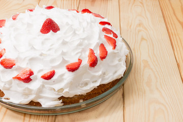 Cake covered with whipped cream decorated with slices of strawberry