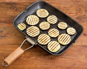 Grilled chopped by circles eggplants on grill pan on table