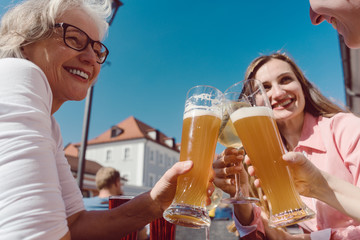 Three women drinking wheat beer on sunny day outdoors