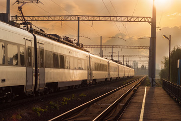 Fototapeta premium Passenger inter-city train in city on the sunset background