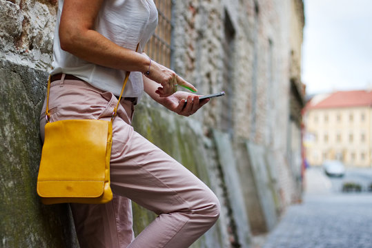Fashionable woman is leaning against wall and using a smartphone 