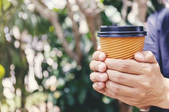 Close-up of male hand holding a paper cup of coffee to take away.