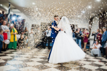 Gorgeous wedding couple performing their first dance with confetti, colorful lights and fireworks.