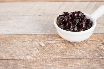 Tapioca Pearl , Bubble topping for tea or other beverage, in a cup, place on wooden table. Copy space