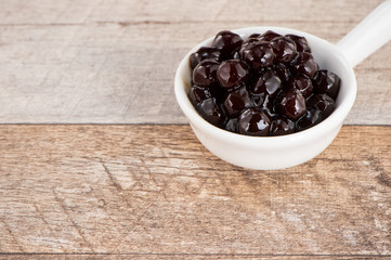 Tapioca Pearl , Bubble topping for tea or other beverage, in a cup, place on wooden table. Copy space