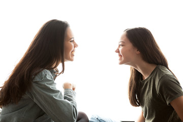 Two sisters playing with each other and having a great time together over white background