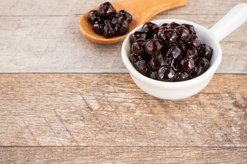 Tapioca Pearl , Bubble topping for tea or other beverage, in a cup, place on wooden table. Copy space